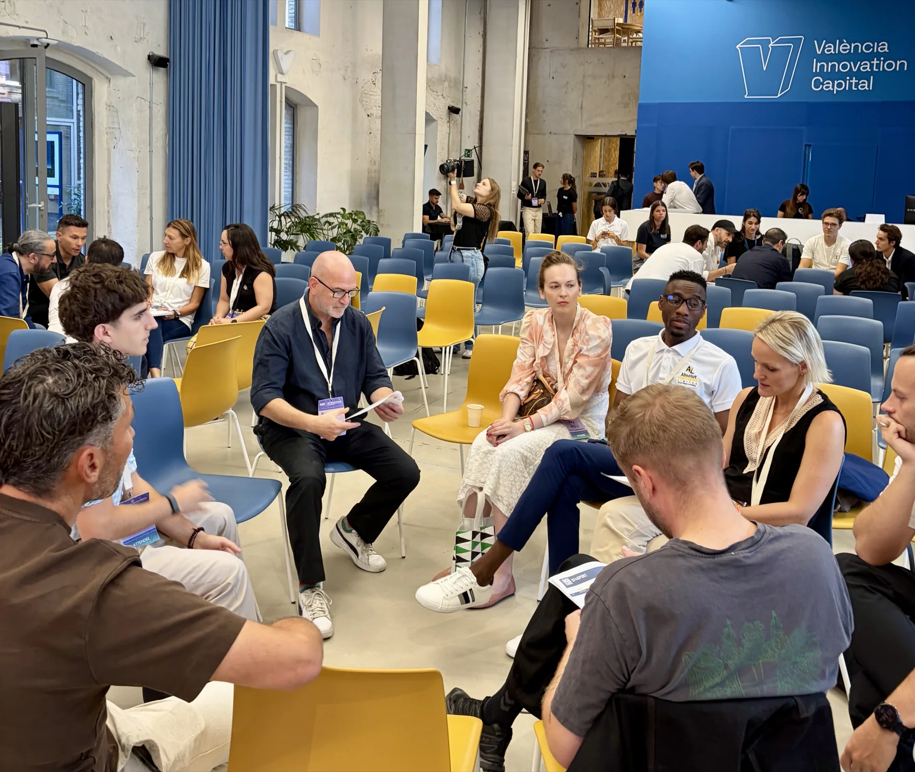 Workshop participants seated in a circle discussing questions and recording ideas.